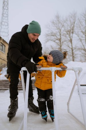 Téléchargez les photos : Papa apprend à son fils à patiner - en image libre de droit