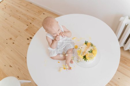 Foto de Bebé niña come pastel de cumpleaños con sus manos y piernas - Imagen libre de derechos