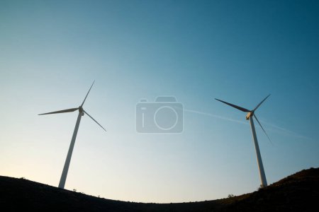 Foto de Silhouettes of wind turbines on a hill at sunrise. - Imagen libre de derechos