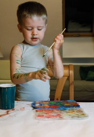 Photo for The boy is engaged in creativity - he paints his hands with paint - Royalty Free Image