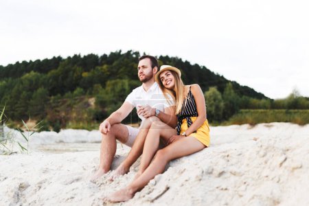 young couple in love are sitting on a sandy beach on vacation