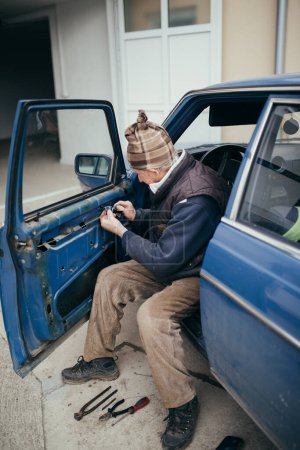 Téléchargez les photos : Le vieux technicien installant la porte de voiture à la maison gros plan - en image libre de droit