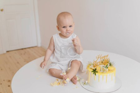 Foto de Bebé niña come pastel de cumpleaños con sus manos y piernas - Imagen libre de derechos