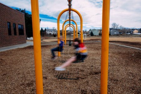 Photo for Two girls swinging at a school - Royalty Free Image