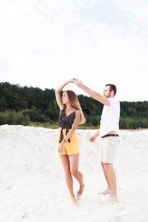 Téléchargez les photos : Man and woman dancing on a warm sandy beach in summer - en image libre de droit