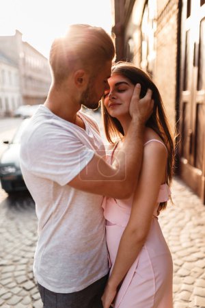 Téléchargez les photos : Homme et jeune femme s'embrassent dans les rayons du soleil couchant dans la ville - en image libre de droit