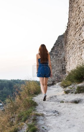 Téléchargez les photos : Femme se promène par les murs du château seul en été - en image libre de droit