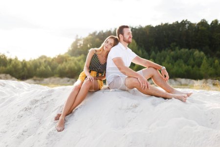 Téléchargez les photos : Couple in love laughing sitting on sandy beach on vacation - en image libre de droit