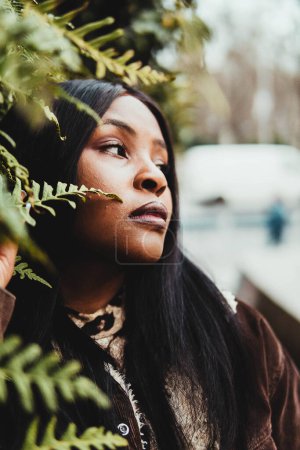 Téléchargez les photos : Portrait of black woman posing among green leaves - en image libre de droit