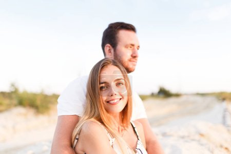 Téléchargez les photos : Man and a woman in light clothes are laughing together on the beach - en image libre de droit