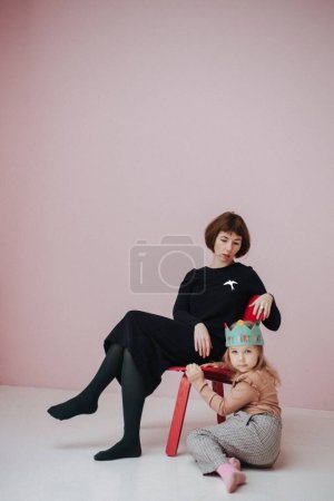 Foto de Mujer en vestido negro y niña sobre fondo rosa - Imagen libre de derechos