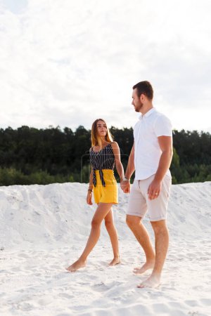 Téléchargez les photos : Man and a woman are walking on a warm sandy beach in the summer - en image libre de droit