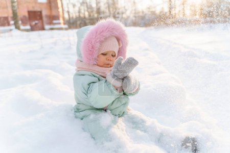 Foto de Retrato de cerca de una linda niña en una menta caliente en la nieve - Imagen libre de derechos