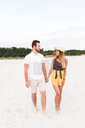 Téléchargez les photos : Man and a woman are walking on a sandy beach in summer - en image libre de droit