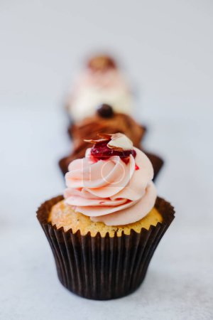 Téléchargez les photos : Line of fresh baked cupcakes with thick frosting - en image libre de droit