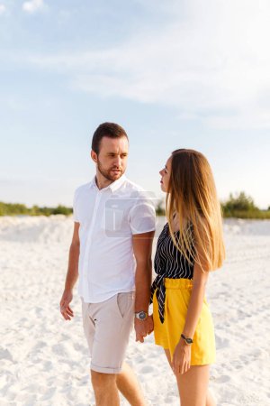 Téléchargez les photos : Man and a woman are walking holding each other on a sandy beach - en image libre de droit