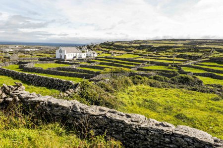 Téléchargez les photos : Church among stone walls of small island town of Ireland. - en image libre de droit