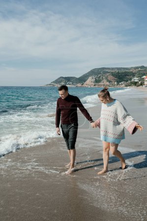 Téléchargez les photos : Couple en vêtements marchant sur la plage - en image libre de droit