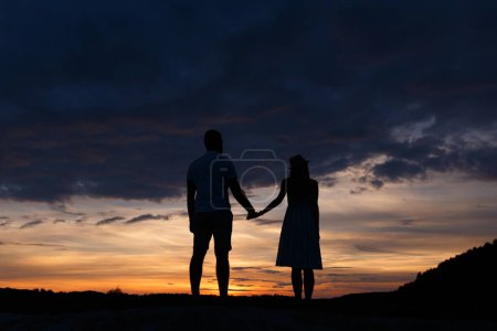 Couple debout tenant la main au coucher du soleil d'été