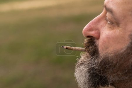 Foto de Hombre fumando un cigarrillo de marihuana de perfil - Imagen libre de derechos