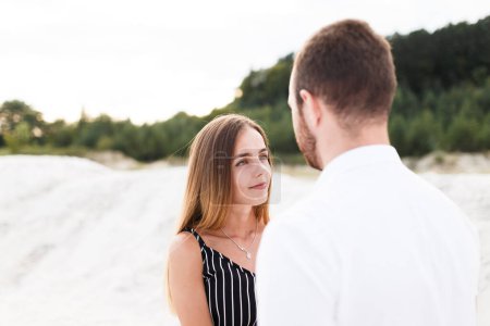 Téléchargez les photos : Young blonde woman looks at her partner on a sunny beach - en image libre de droit