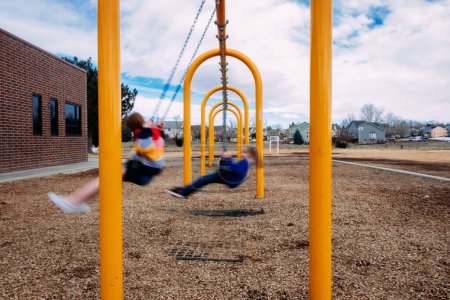 Photo for Blurry children swinging on swings outside - Royalty Free Image