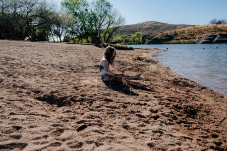 Photo for Tween girl playing in sand at a lake - Royalty Free Image