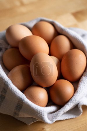 Foto de Foto de cerca de los huevos marrones en la encimera de madera de cocina en una toalla - Imagen libre de derechos