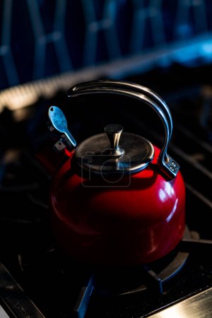 Foto de Tetera roja en estufa negra parte superior dentro de casa - Imagen libre de derechos