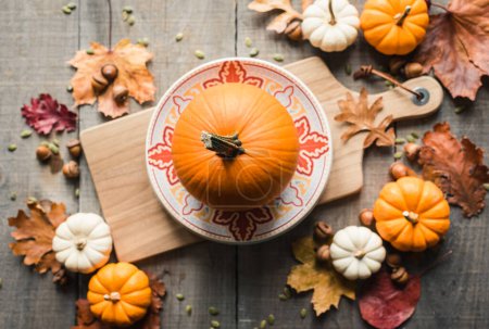 Photo for Overhead view of pumpkin on a plate on a wooden board on a table. - Royalty Free Image