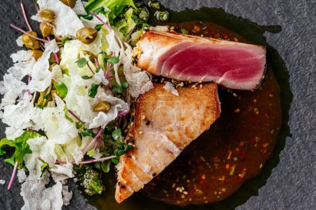 Téléchargez les photos : Steak de thon grillé avec sauce dans une assiette sur une table en bois - en image libre de droit