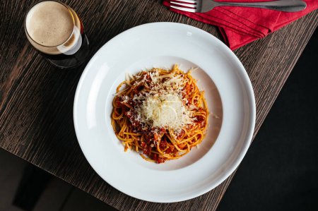 Photo for Pasta bolognese in a white plate on a dark table in a restaurant - Royalty Free Image