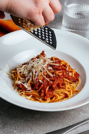 Photo for Chef rubs parmesan cheese into pasta bolognese - Royalty Free Image