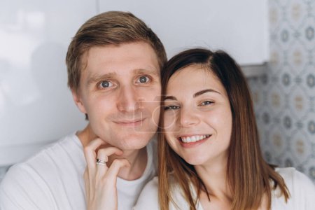 Téléchargez les photos : Gros plan d'un couple souriant d'amoureux sur une cuisine blanche - en image libre de droit