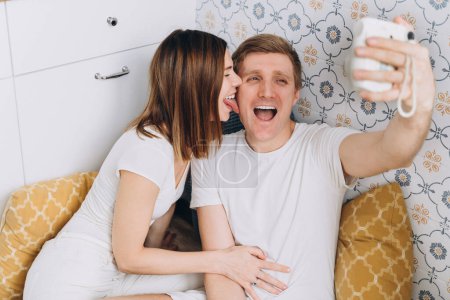 Foto de Una pareja en la cocina toma una estúpida selfie divertida en una cámara instantánea - Imagen libre de derechos