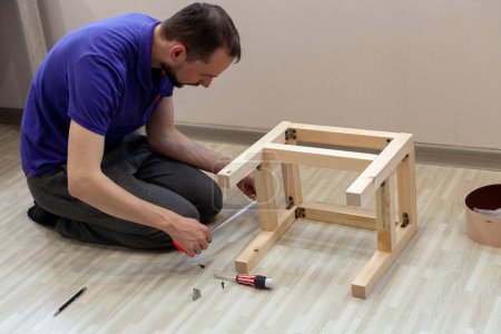 Foto de El hombre con una cinta métrica mide el detalle del taburete de madera - Imagen libre de derechos