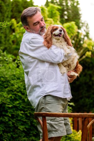 Téléchargez les photos : Portrait d'un homme âgé avec son chien dans le jardin. - en image libre de droit