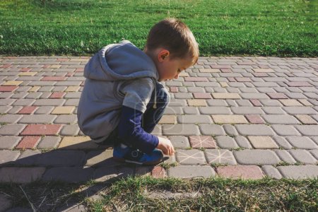 Photo for Boy using sidewalk chalk on a walkway - Royalty Free Image