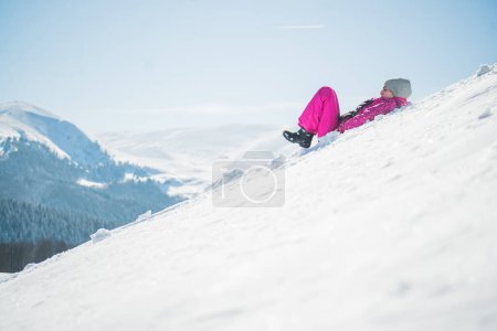 Téléchargez les photos : Hiver glissant fille sur pente raide dans les montagnes - en image libre de droit