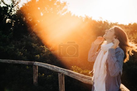 Téléchargez les photos : Une fille ludique et souriante profitant de la lumière du coucher du soleil - en image libre de droit