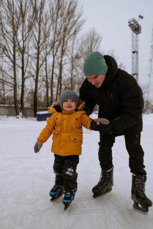 Téléchargez les photos : Père apprend à son fils à patiner - en image libre de droit