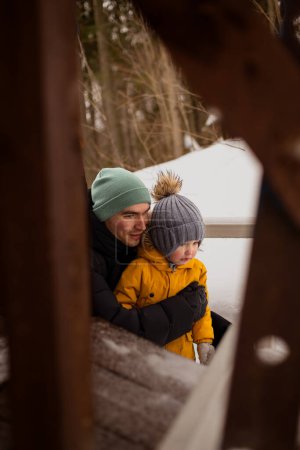 Téléchargez les photos : Papa et fils regardant quelque chose dans la forêt d'hiver - en image libre de droit