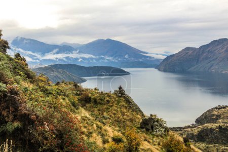 Foto de Hombre sentado en el pico de la montaña mirando sobre el lago en Nueva Zelanda. - Imagen libre de derechos