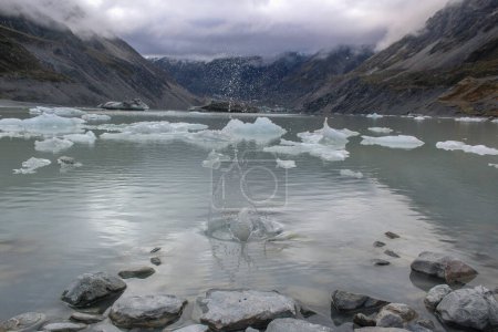 Téléchargez les photos : Éclaboussures de roche dans les eaux glaciaires entourées de montagnes en Nouvelle-Zélande - en image libre de droit