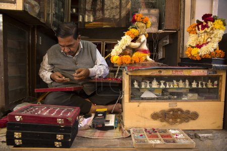 Téléchargez les photos : Un bijoutier dans un bazar de bijoux exhibe son commerce depuis sa petite boutique dans la vieille ville de Jodhpur - en image libre de droit