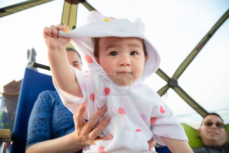 Foto de Bebé niña se sienta mirando hacia adelante mientras tira de la toalla encapuchada de su cara - Imagen libre de derechos