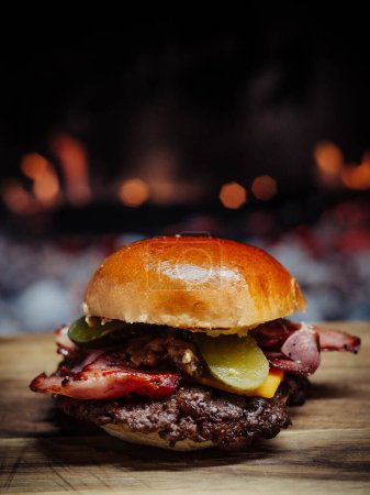 Téléchargez les photos : Smashed Cheeseburger on a wooden table in front of a fireplace. - en image libre de droit