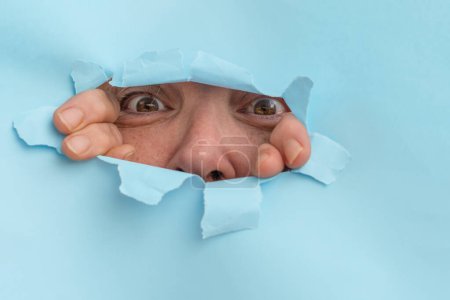 Photo for Woman looking through a hole in a cardboard - Royalty Free Image