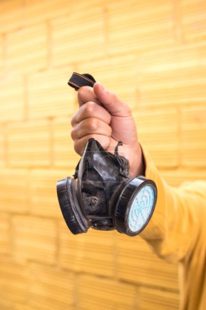 Foto de Hombre sosteniendo una máscara de gas sobre fondo amarillo - Imagen libre de derechos