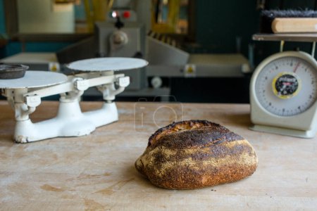 Photo for Fresh-baked bread sits on floured counter with antique kitchen scales - Royalty Free Image